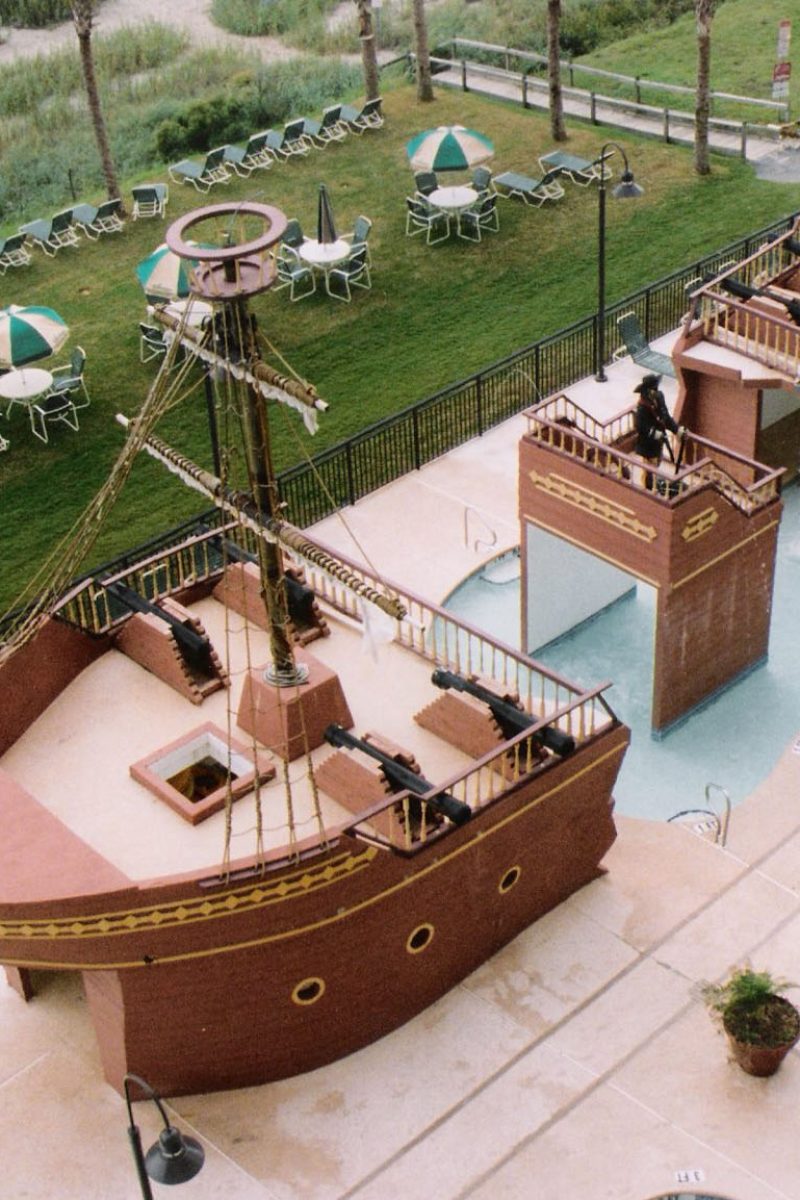 A truly impressive commercial poolscape modeled to look like a full-fledged pirate ship separated into 3 distinct parts while a shallow wading pool connects each section.